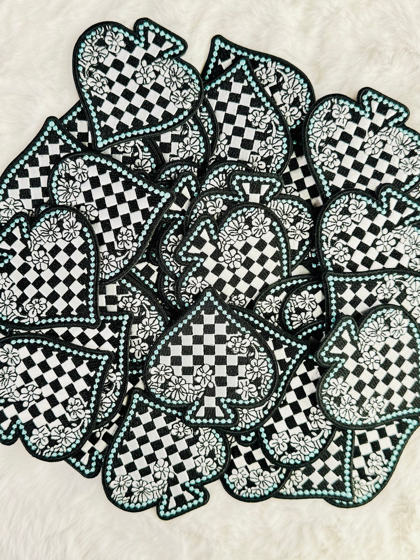 A stack of the Black & White Checkered Floral Spade Embroidered Patch