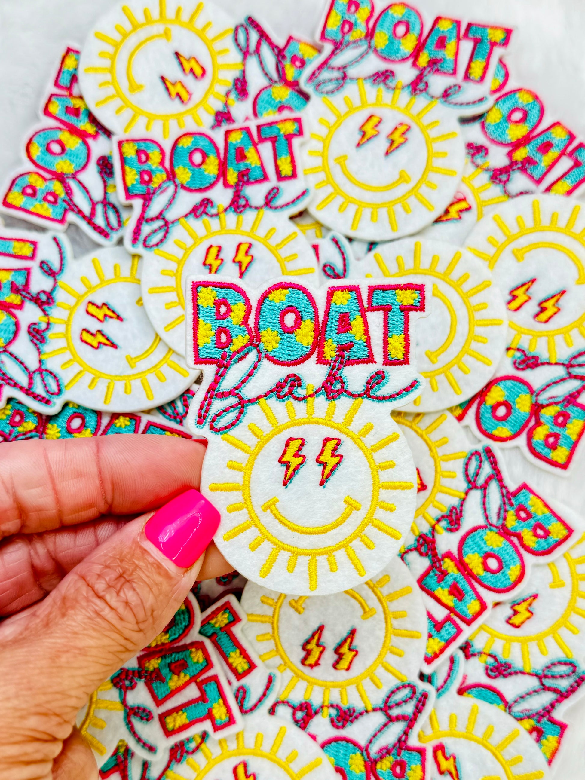 A close up of the Smiley Sunny boat babe embroidered trucker patch