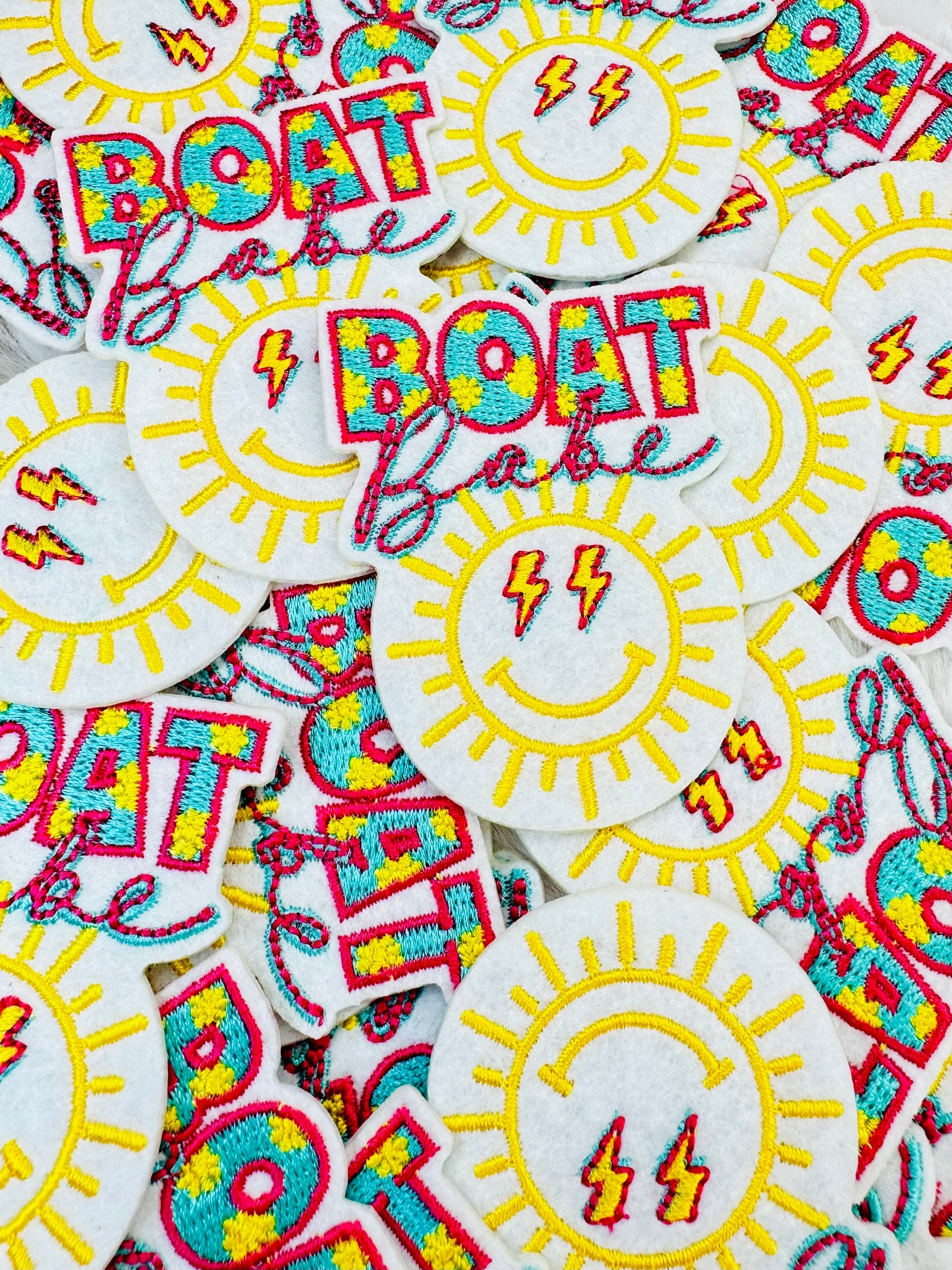 A stack of the Smiley Sunny boat babe embroidered trucker patch