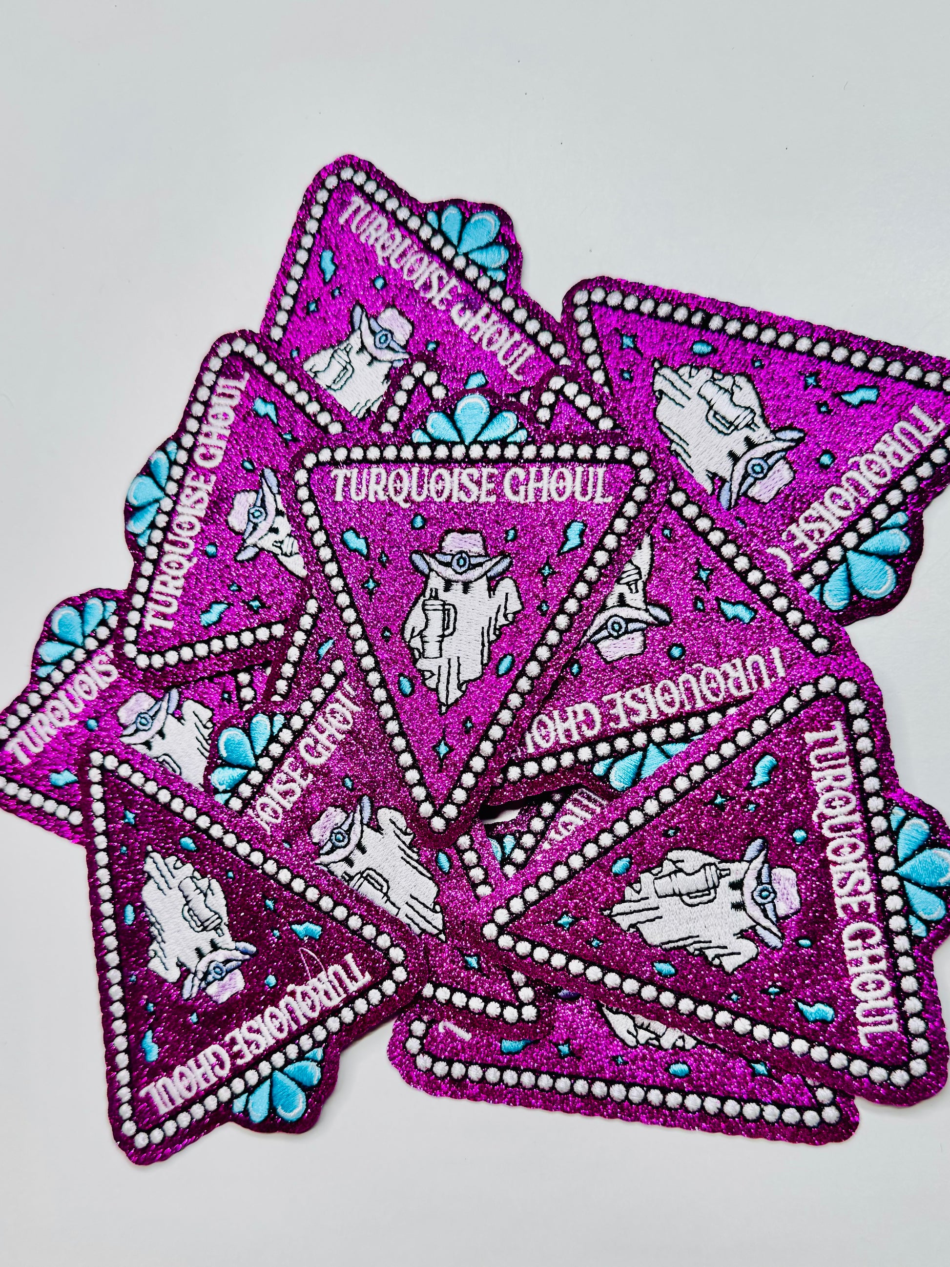 A stack of the turquoise ghoul glitter embroidered patch